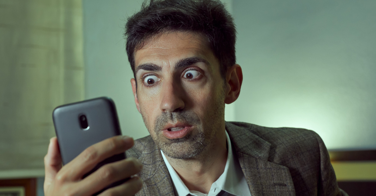 Scared man looking at phone