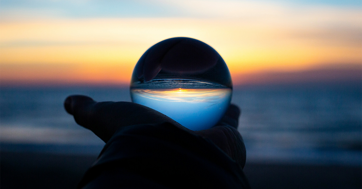 person holding a crystal ball reflecting a horizon