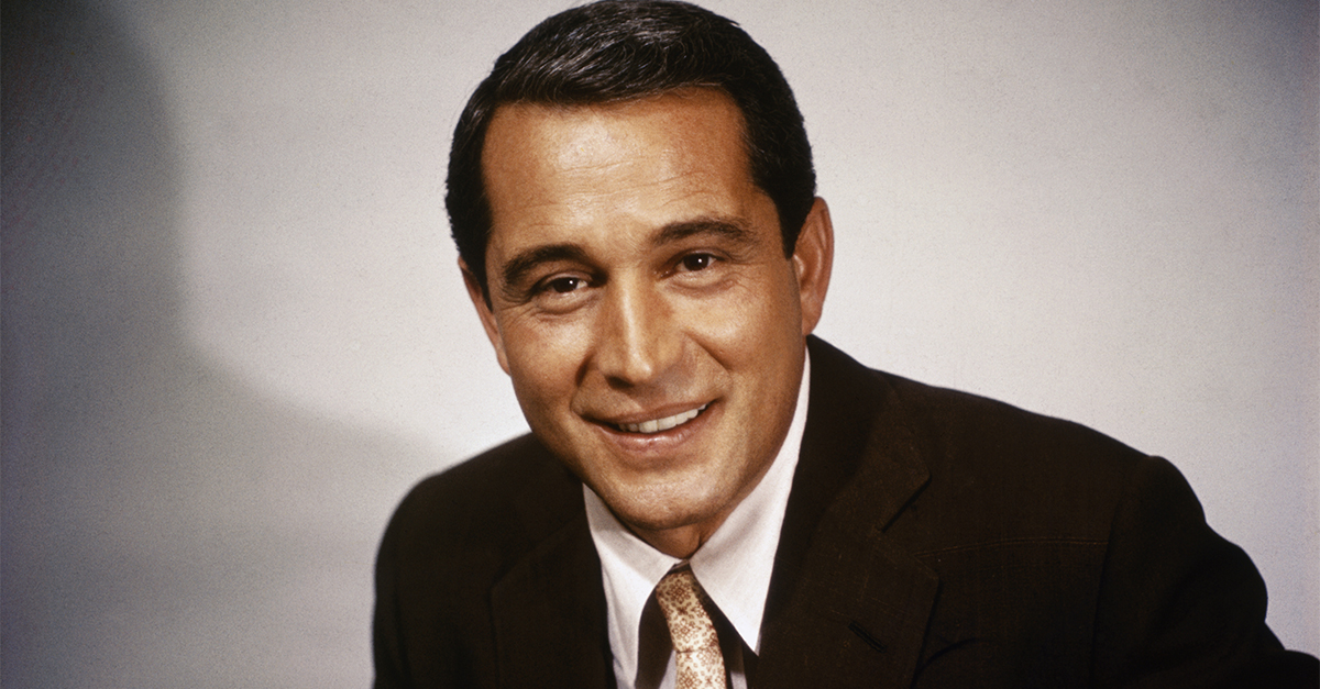 Closeup of Perry Como, he is depicted waist up in suit and tie, smiling.