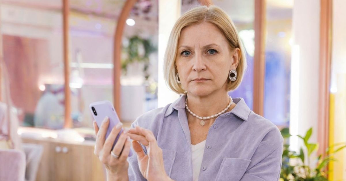 Adult woman in a purple blouse holding an iphone