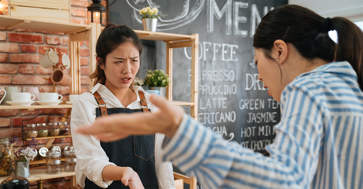 emotional female customer arguing with staff girl at bar counter.