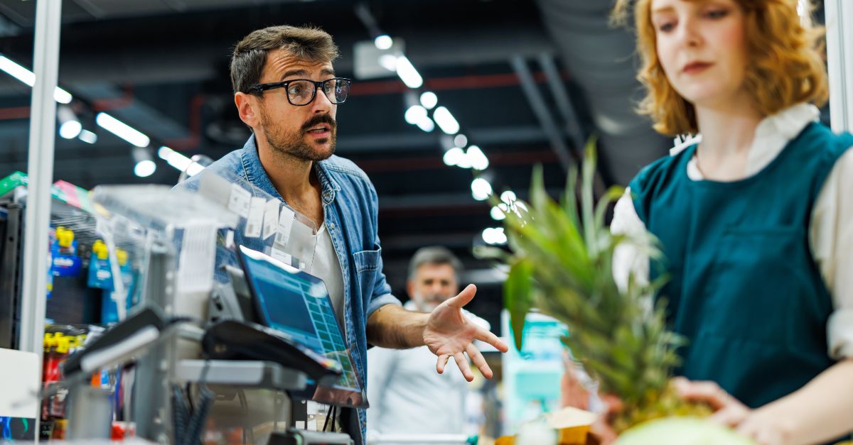 Frustrated customer arguing with cashier over high prices at supermarket checkout