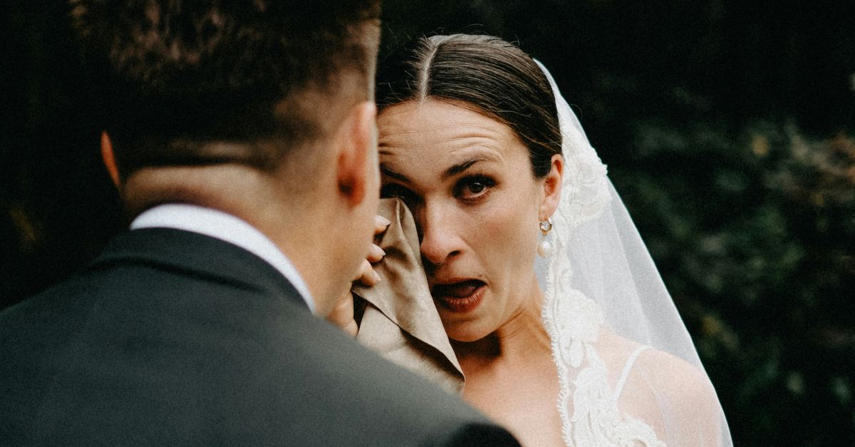 Bride cries while wiping eyes with cloth.