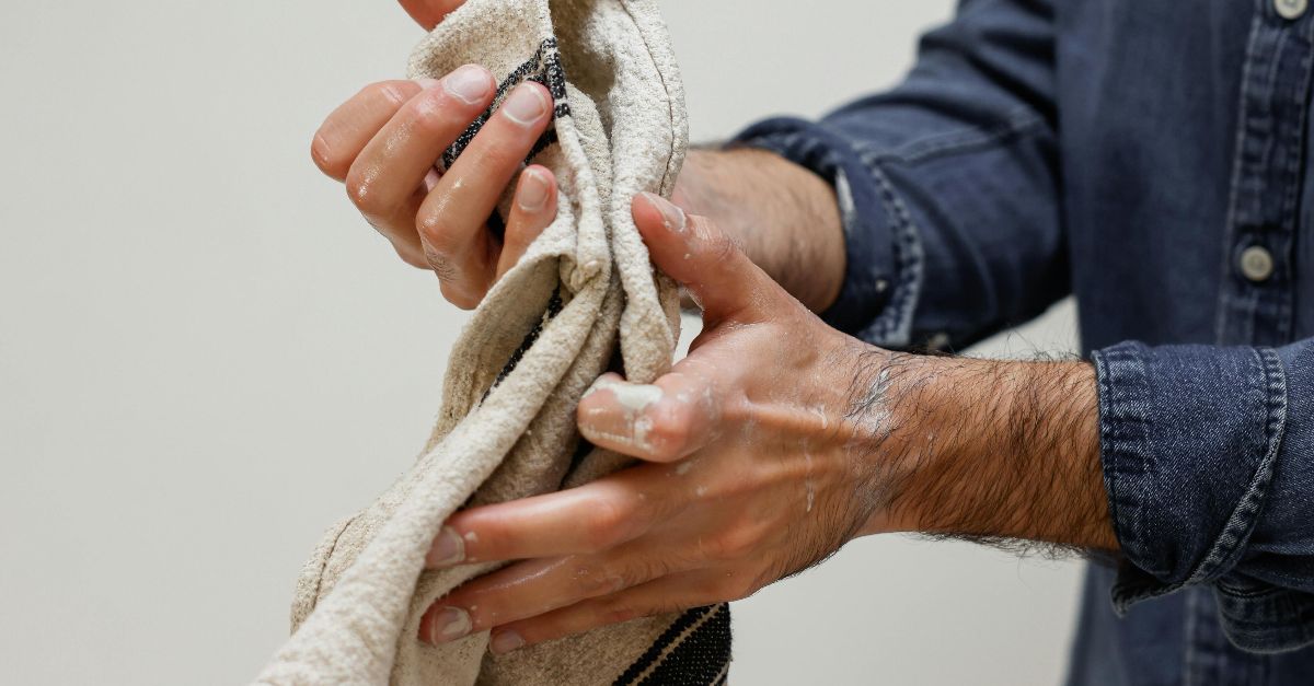 Close-up of hands cleaning mud with a towel indoors, showing detailed cleaning action.