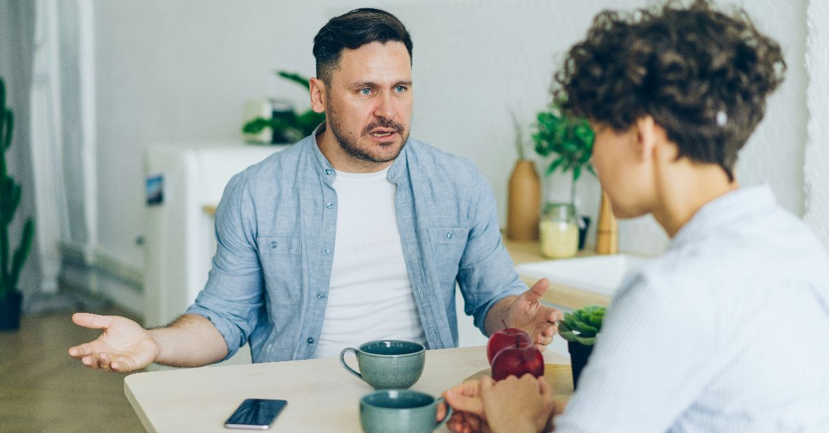 a man sitting at a table talking to a woman