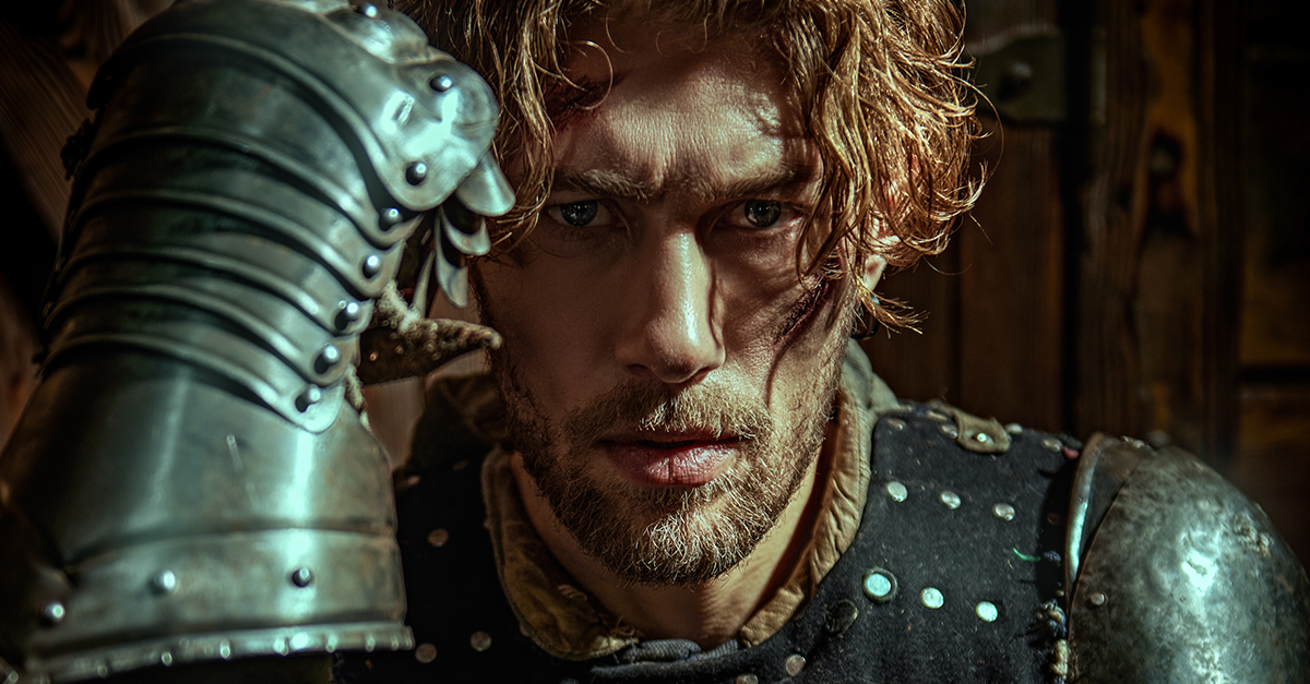 A handsome noble medieval knight in armor standing in a castle. Historical reconstruction.