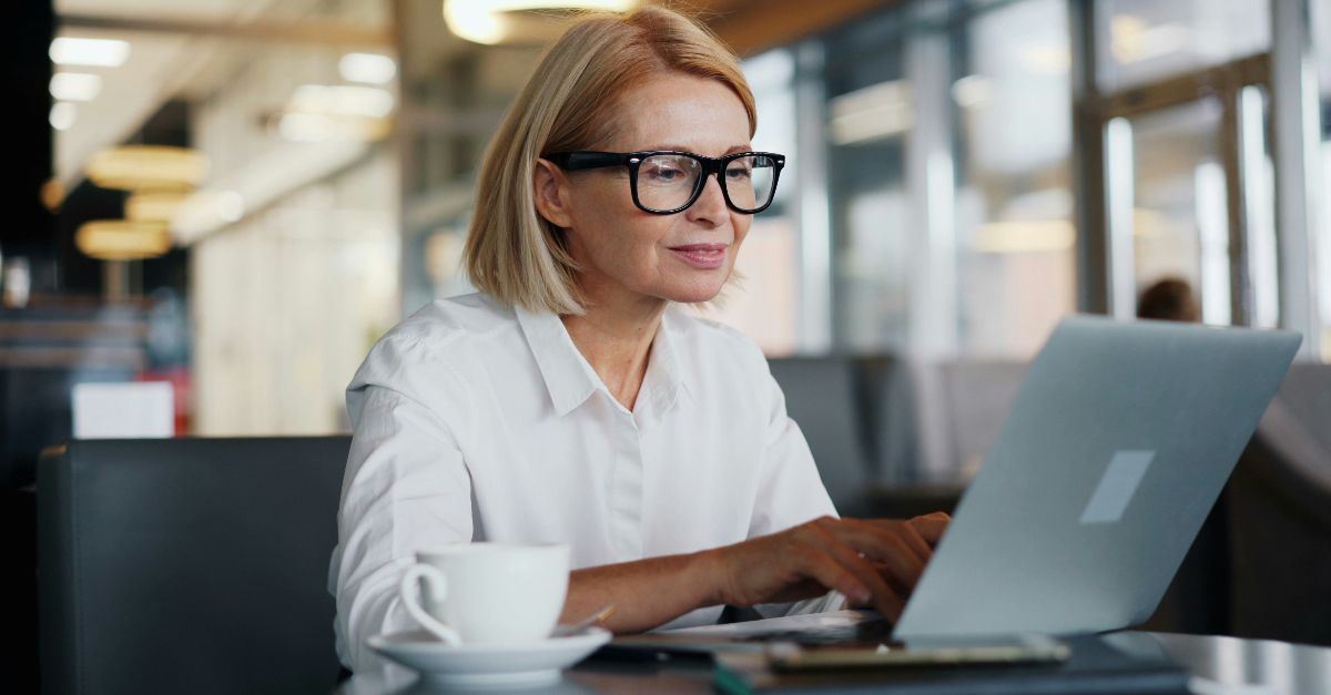 a woman sitting at a table using a laptop computer