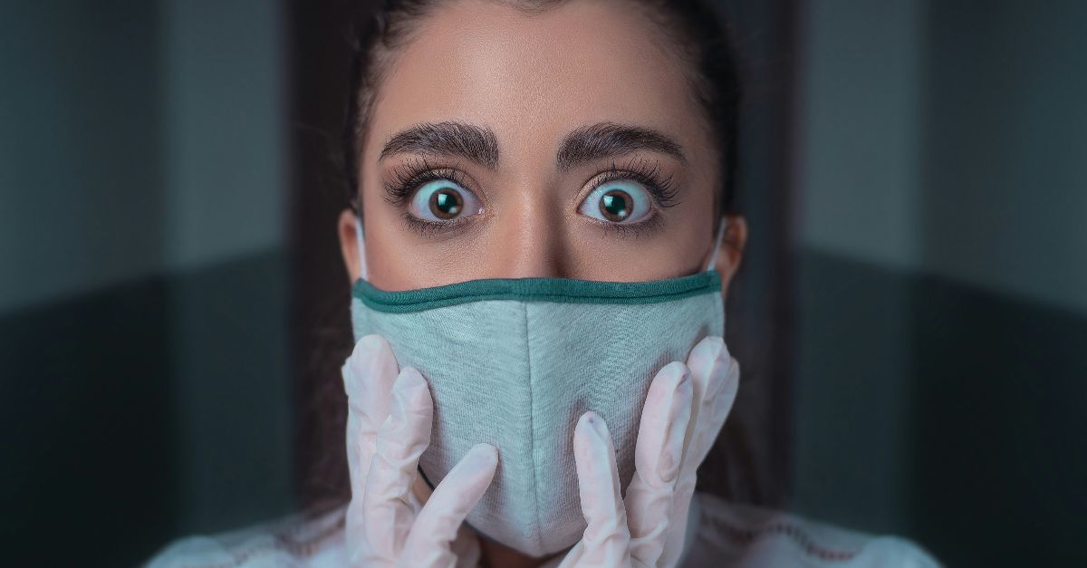 woman in white long sleeve shirt covering her face with blue and black face mask