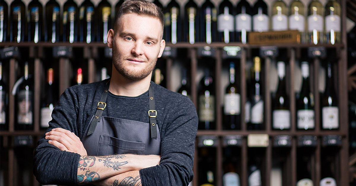 Bearded young man sommelier tasting wine