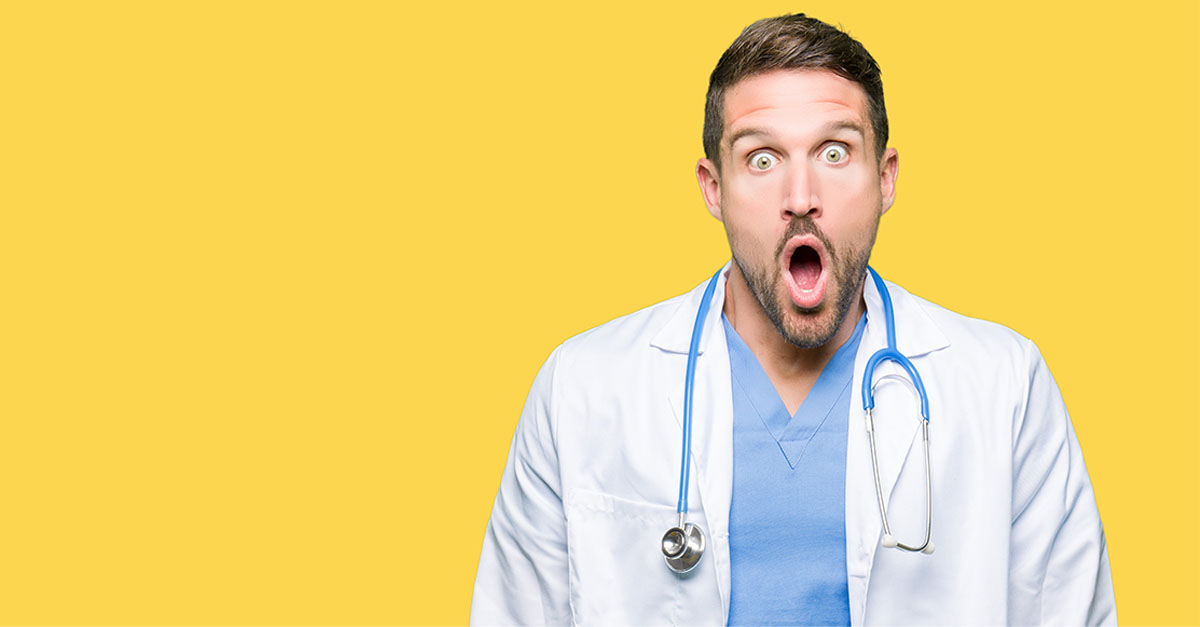 Male doctor wearing medical uniform with shocked expression