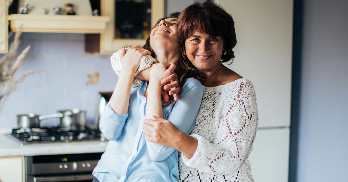 A heartfelt embrace between mother and daughter in a cozy kitchen setting.