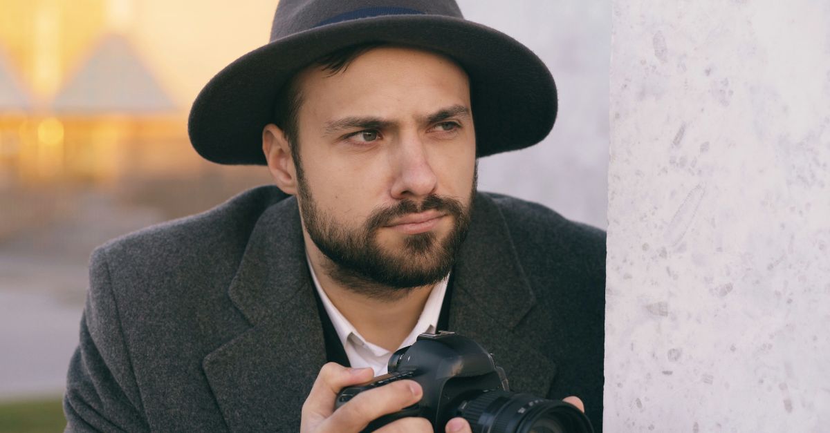 Man in hat holding a camera outdoors