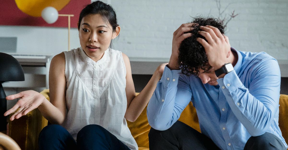 A couple having a serious conversation indoors, expressing emotions and misunderstanding.