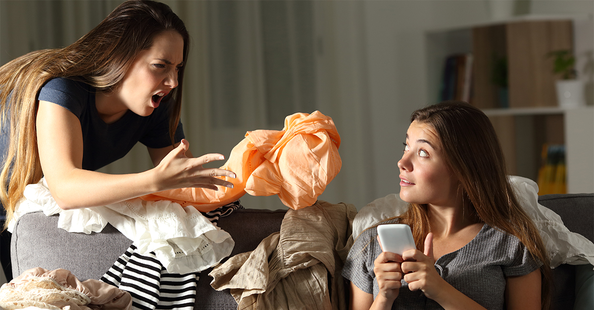 Roommate scolding her messy friend sitting on a couch in the living room at home