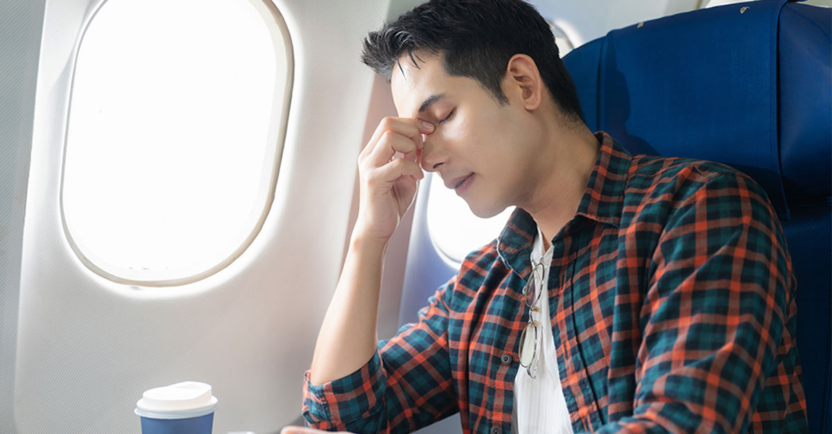 Man with headache while sitting on plane