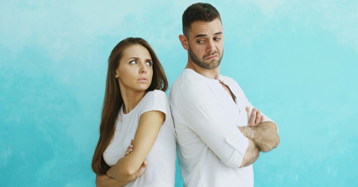 Couple standing back to back with arms crossed