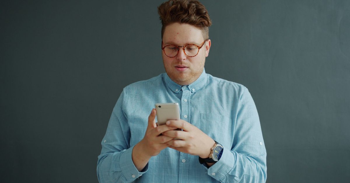 Man in glasses looking at his phone.