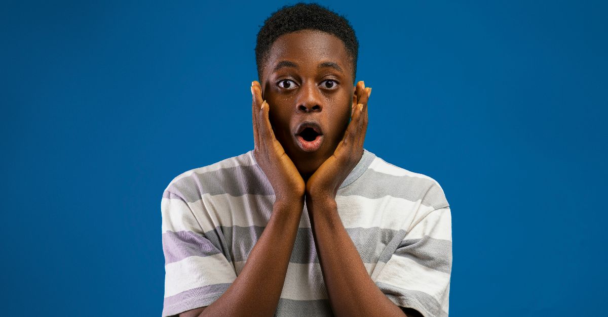 a boy making a surprised face with his hands