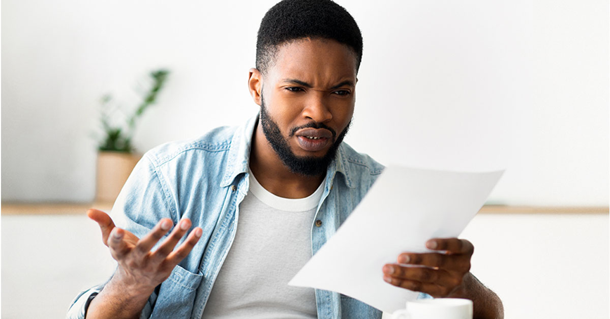man sits at a desk and looks surprised, reacting to paper